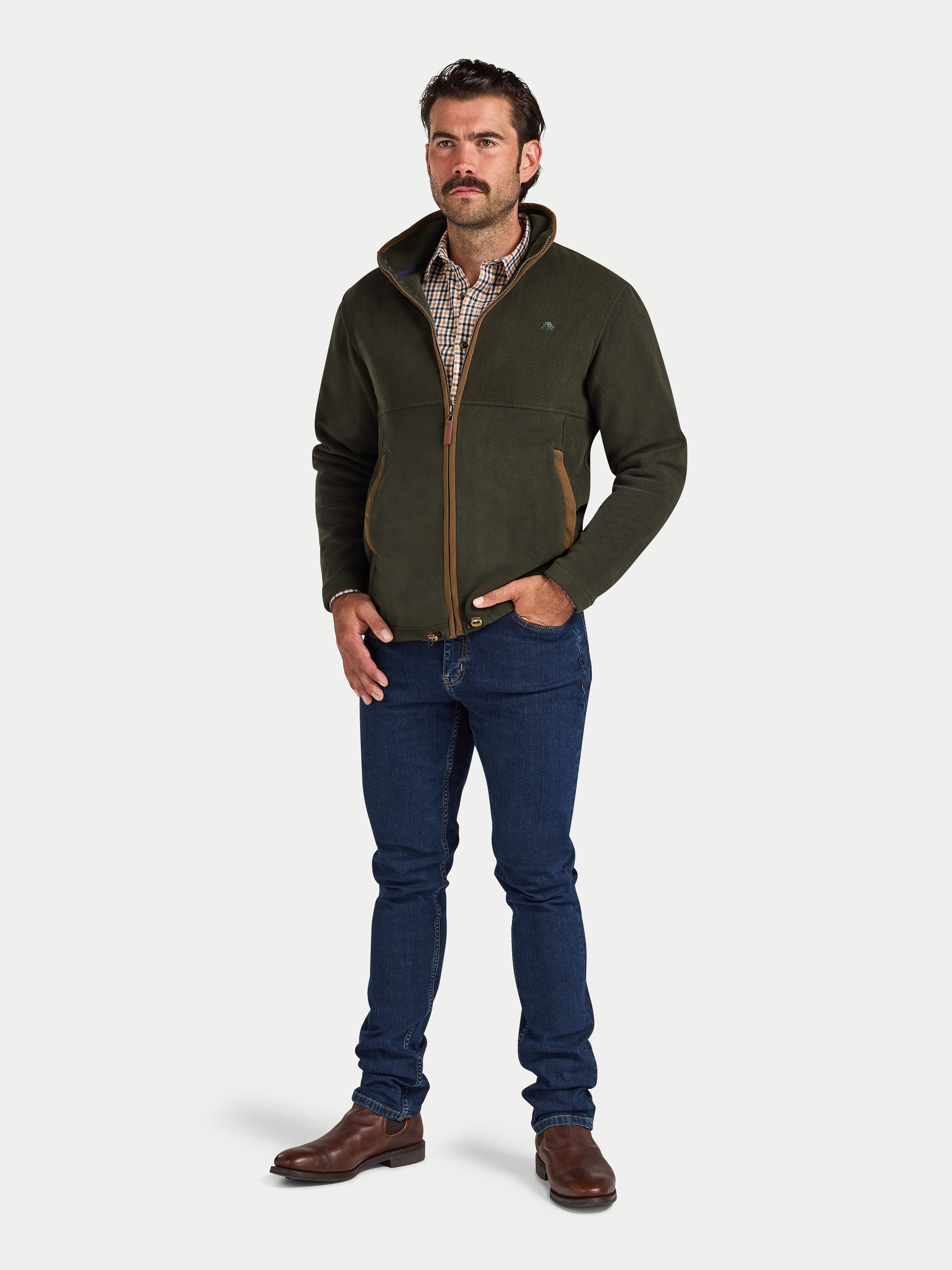 Man wearing a green fleece jacket, plaid shirt, and blue jeans on a white background