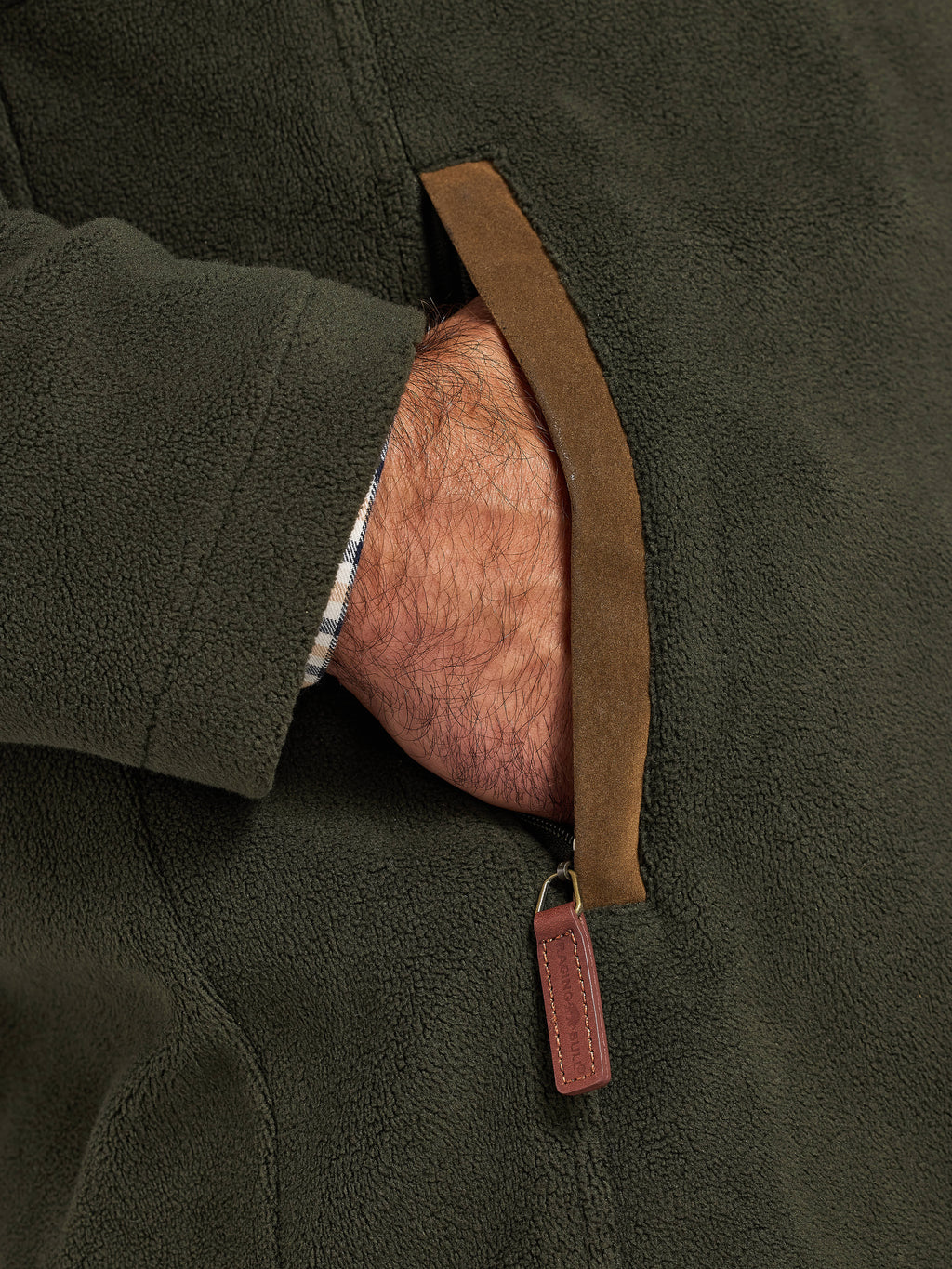 Close-up of a person wearing a dark green fleece jacket with a brown leather strap.