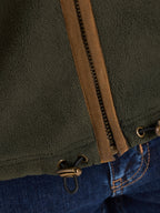 Close-up of a green jacket with a brown zipper and blue jeans.
