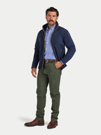 Man wearing a navy jacket, blue checkered shirt, and green pants on a white background
