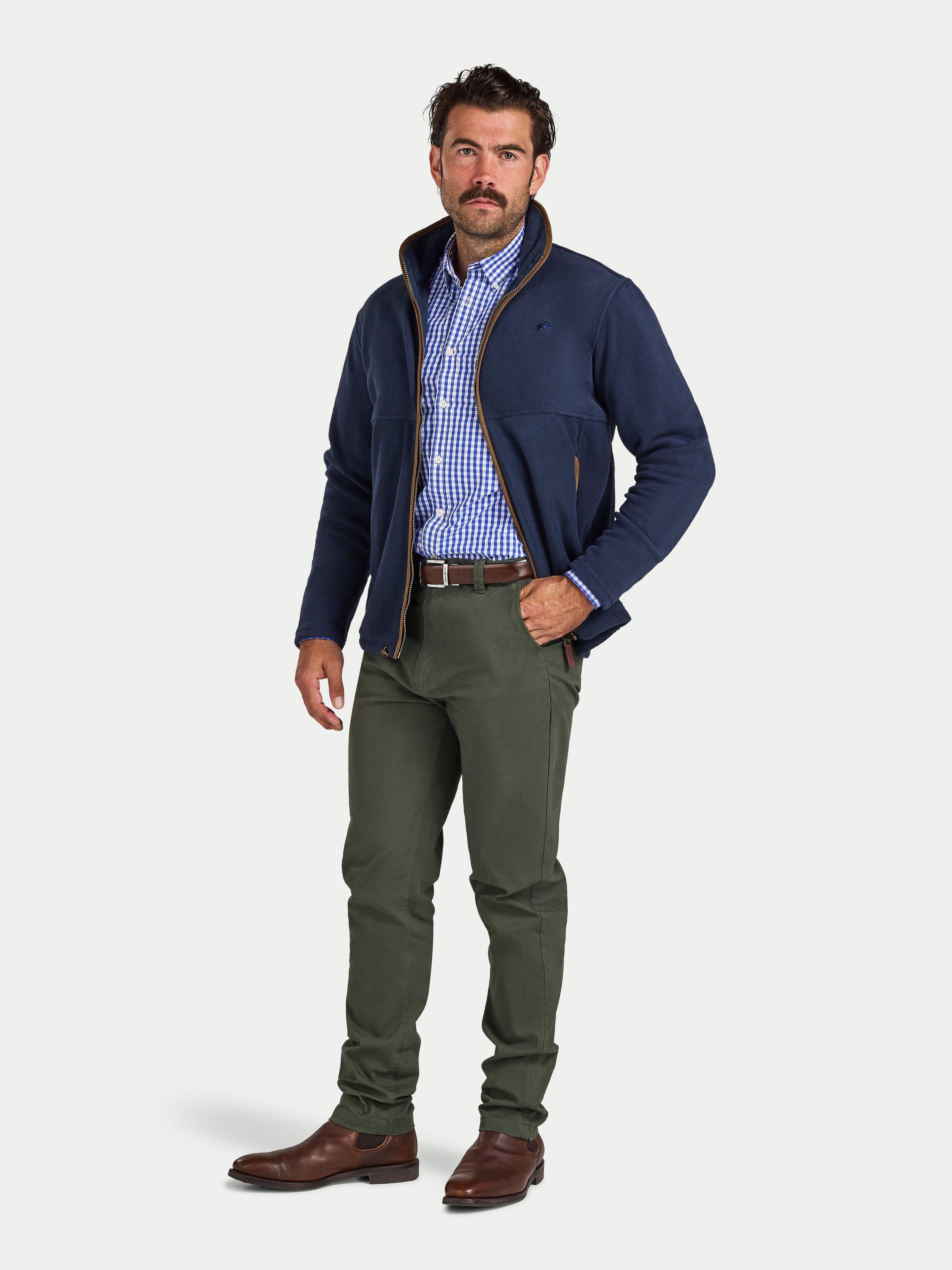 Man wearing a navy jacket, blue checkered shirt, and green pants on a white background