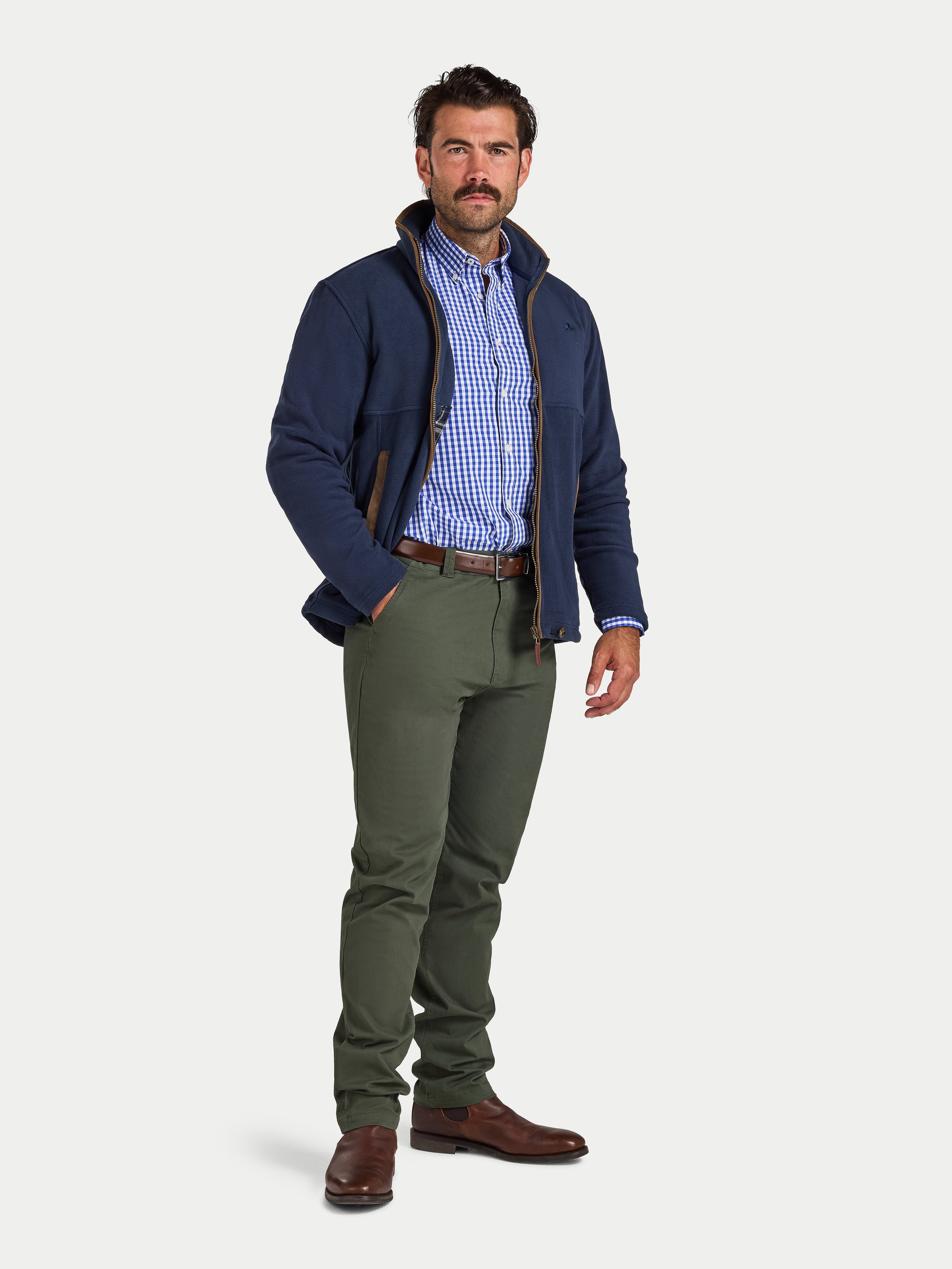 Man wearing a navy jacket, checkered shirt, and green pants on a white background