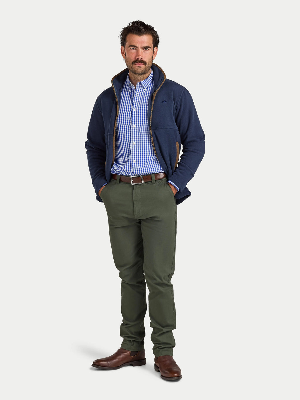 Man wearing a navy jacket, checkered shirt, and green pants on a white background