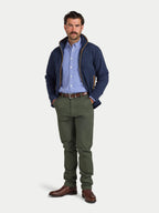 Man wearing a navy jacket, checkered shirt, and green pants on a white background