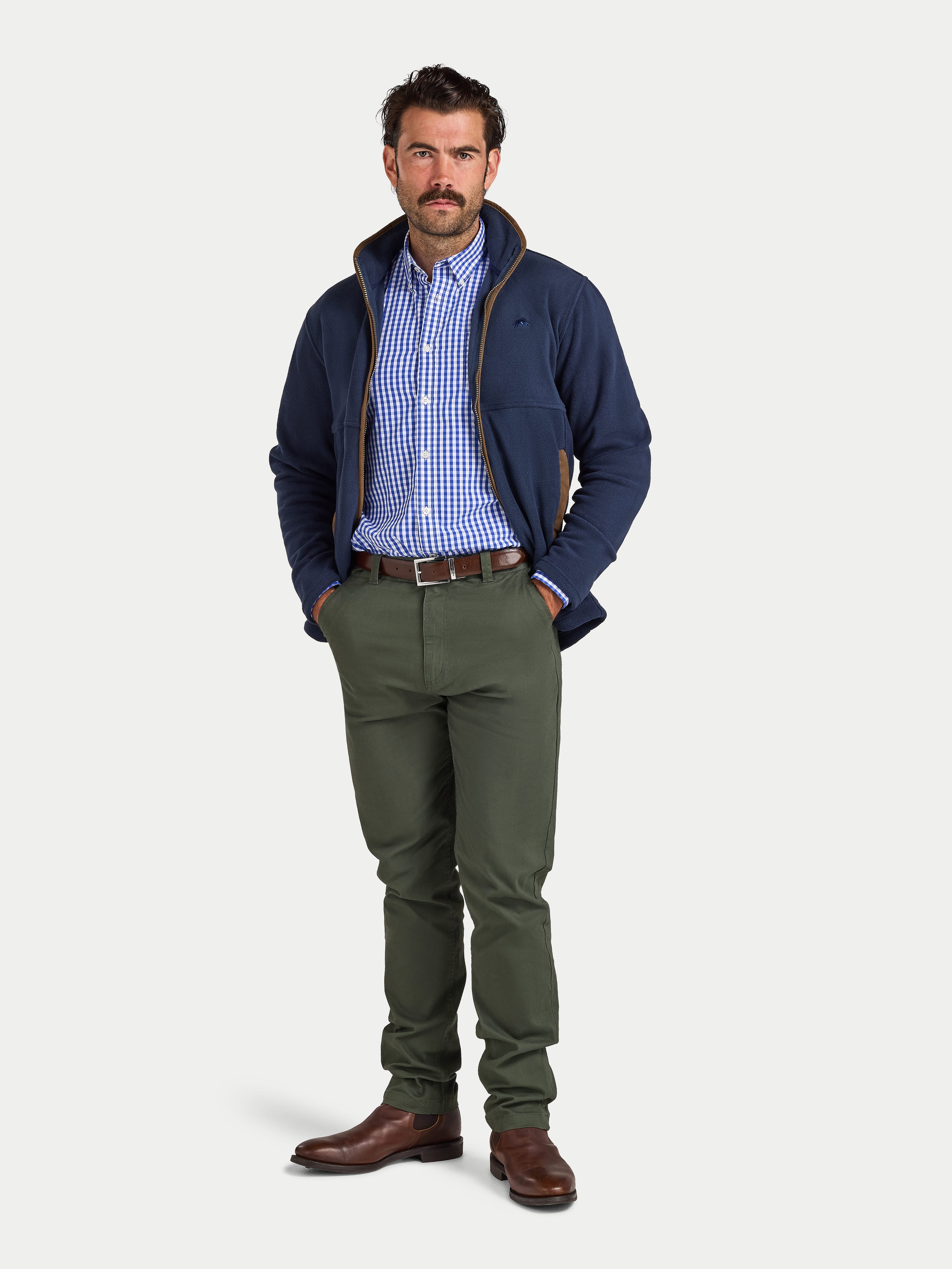 Man wearing a navy jacket, checkered shirt, and green pants on a white background