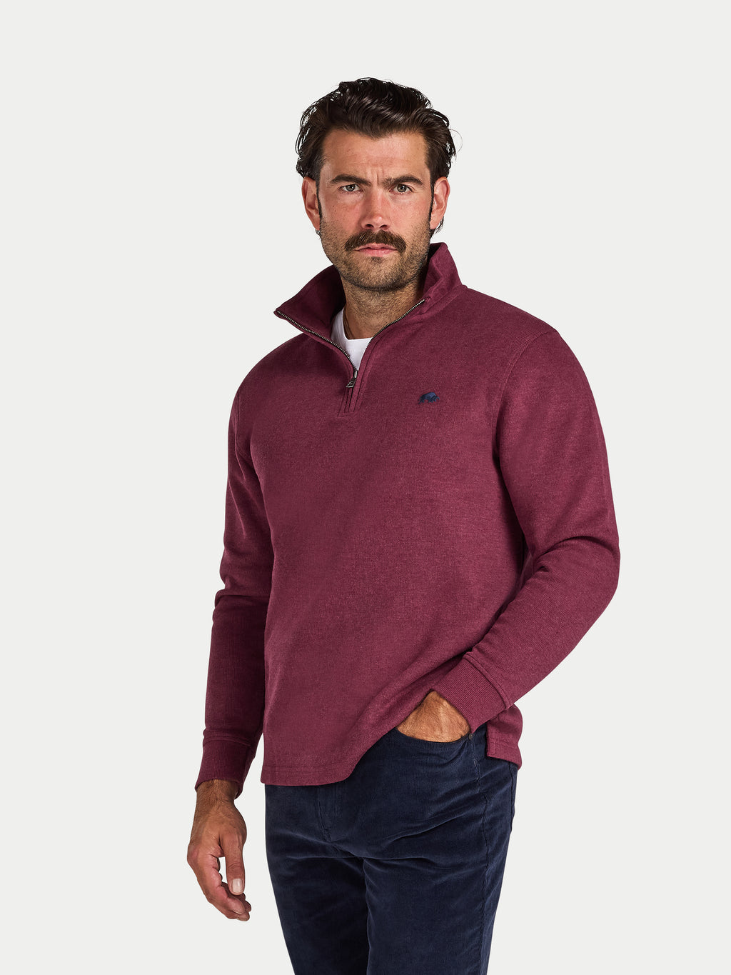 Man wearing a burgundy pullover with a small logo on a white background