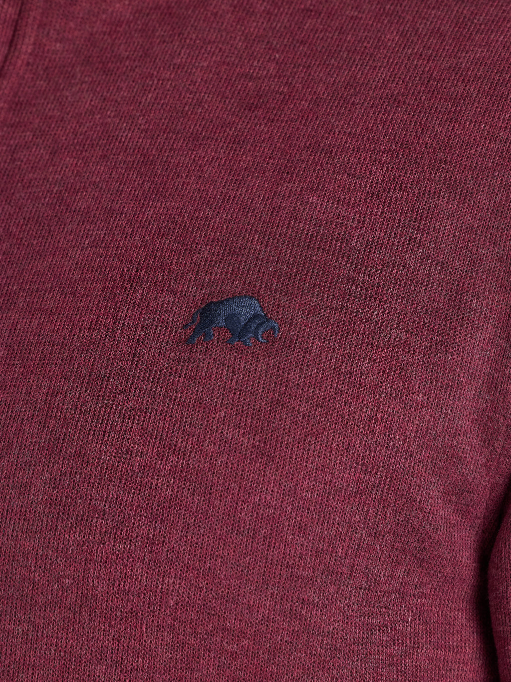 Close-up of a maroon sweater with a small dark blue logo on a plain background