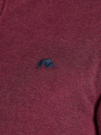 Close-up of a maroon sweater with a small dark blue logo on a plain background