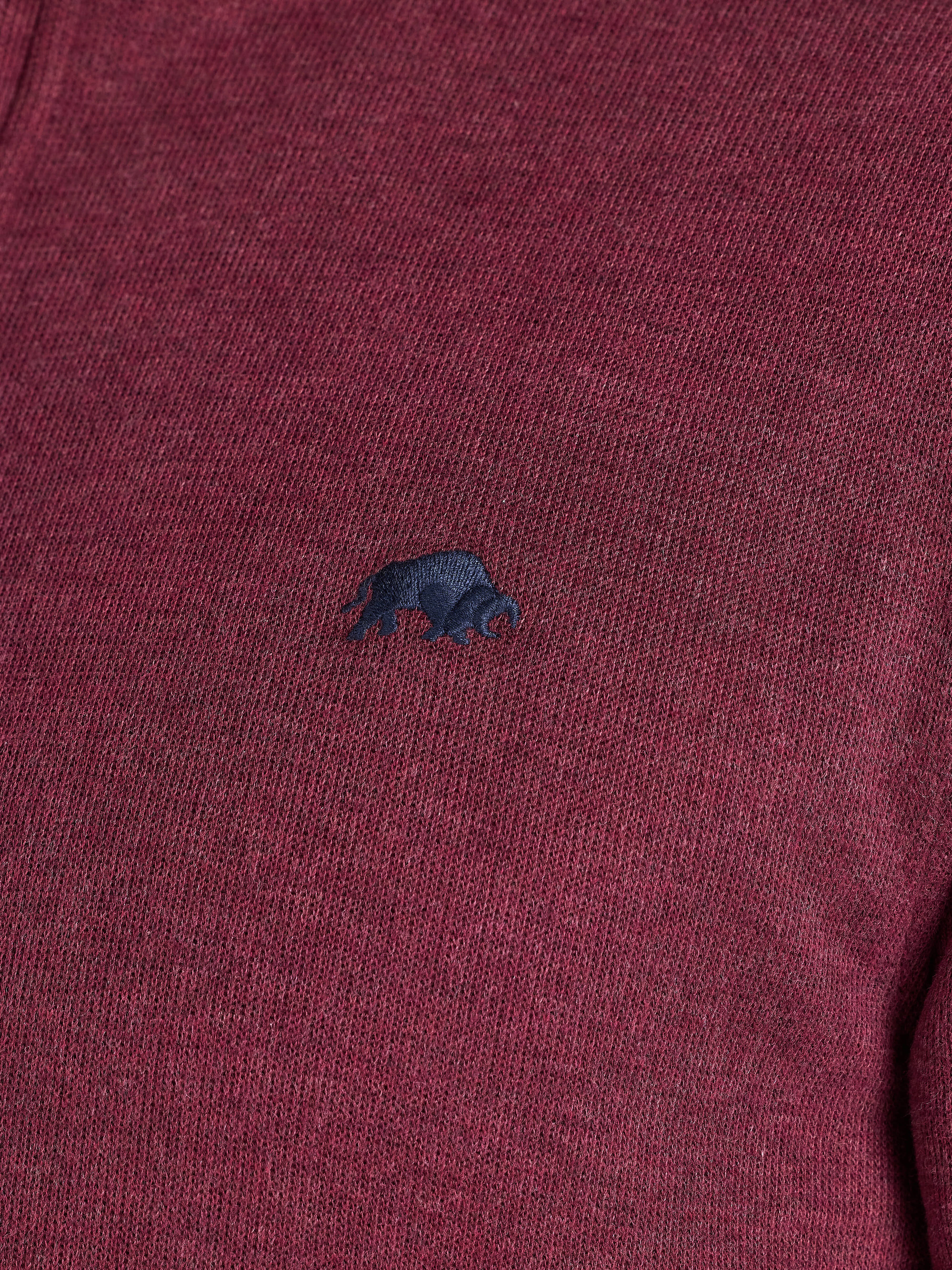 Close-up of a maroon sweater with a small dark blue logo on a plain background