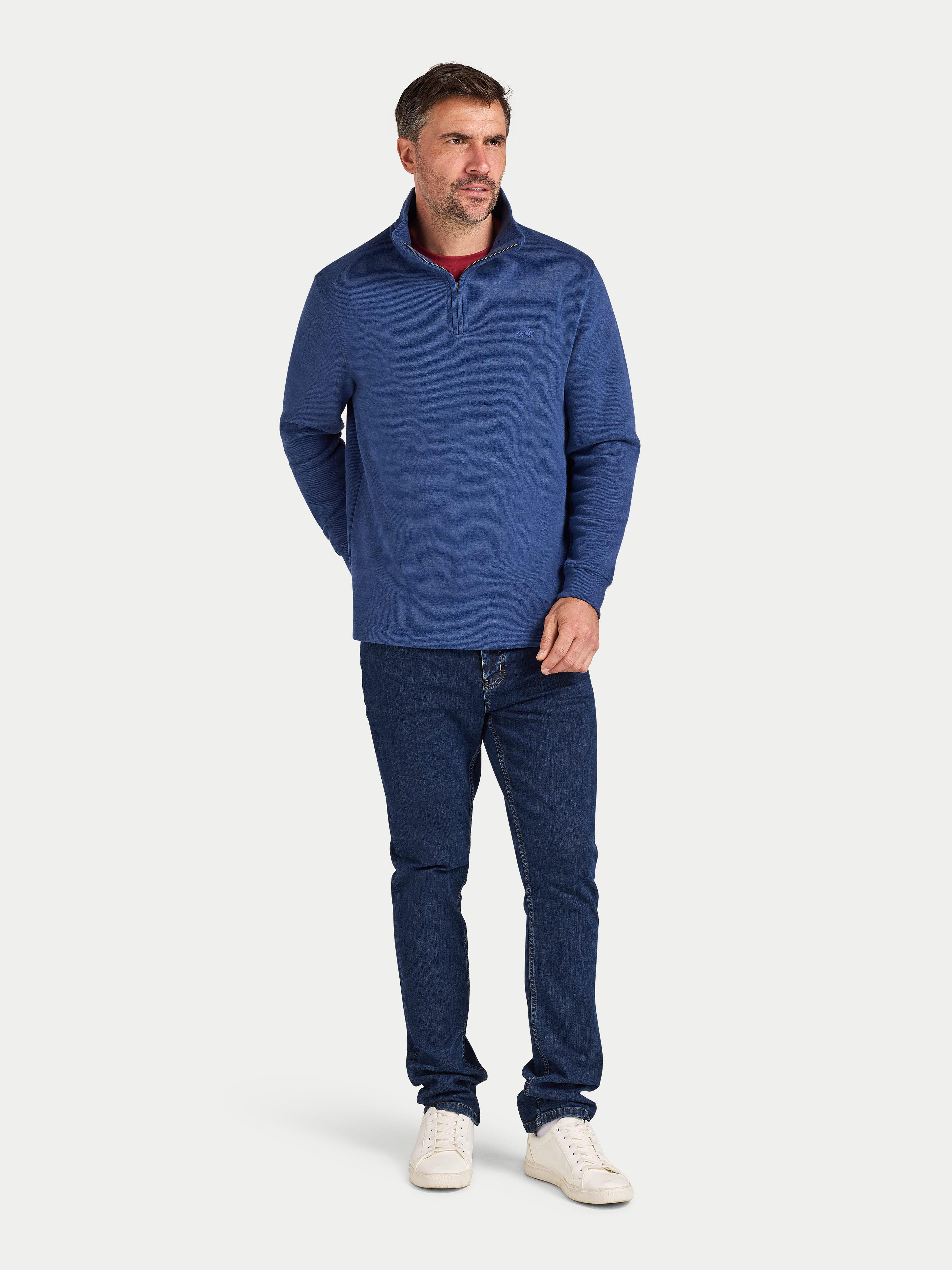 Man wearing a blue sweater and jeans on a white background