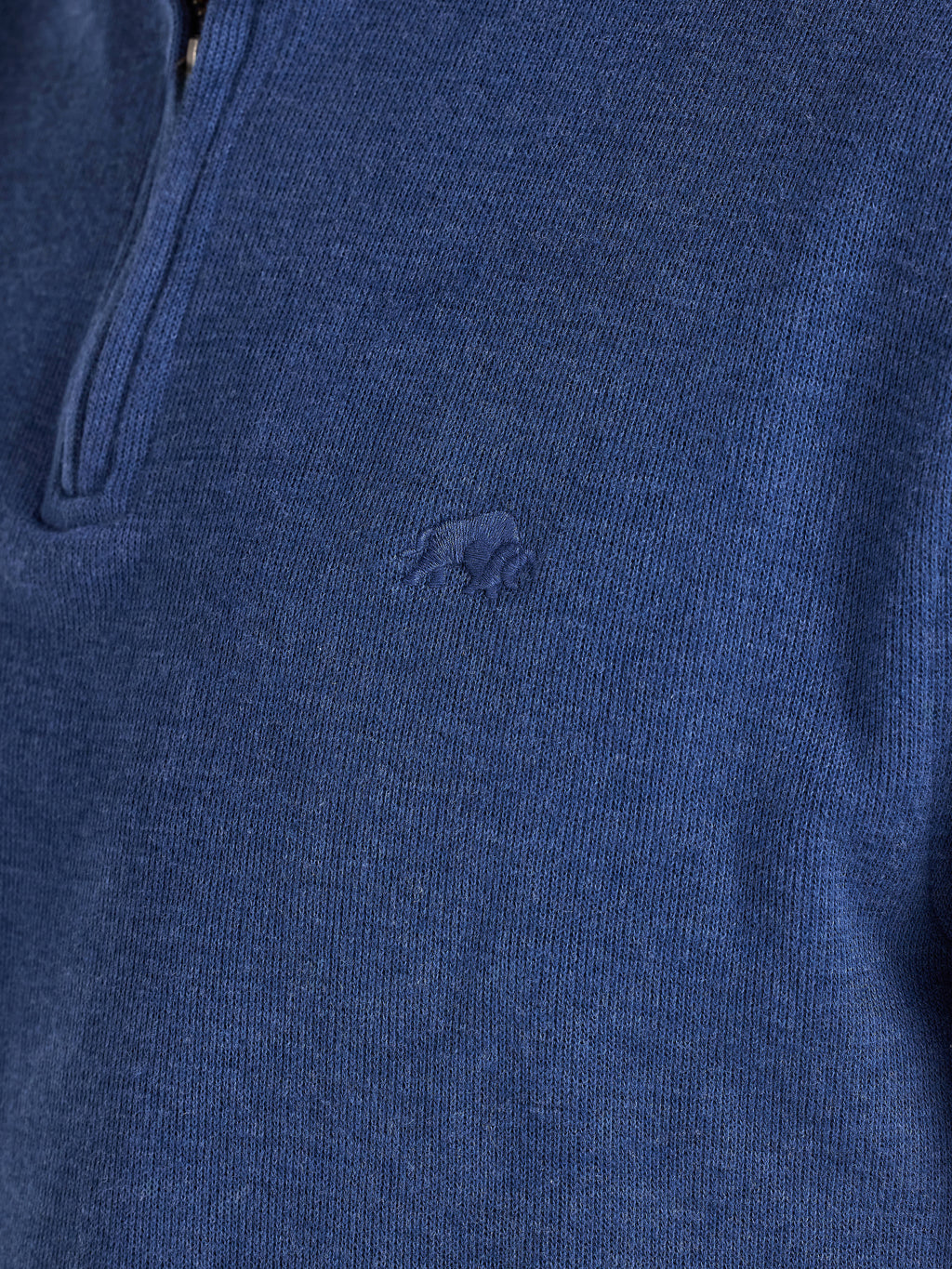 Close-up of a blue sweater with a brand logo on a dark background