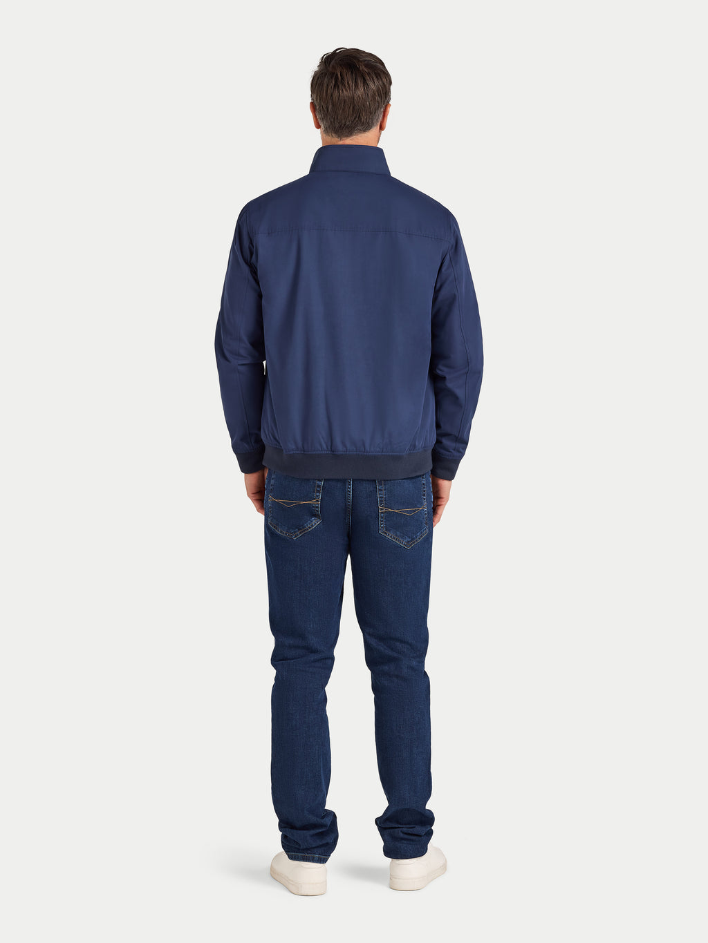 Man wearing a blue jacket and jeans on a white background