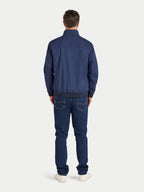 Man wearing a blue jacket and jeans on a white background