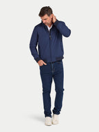 Man wearing a navy jacket and jeans on a white background