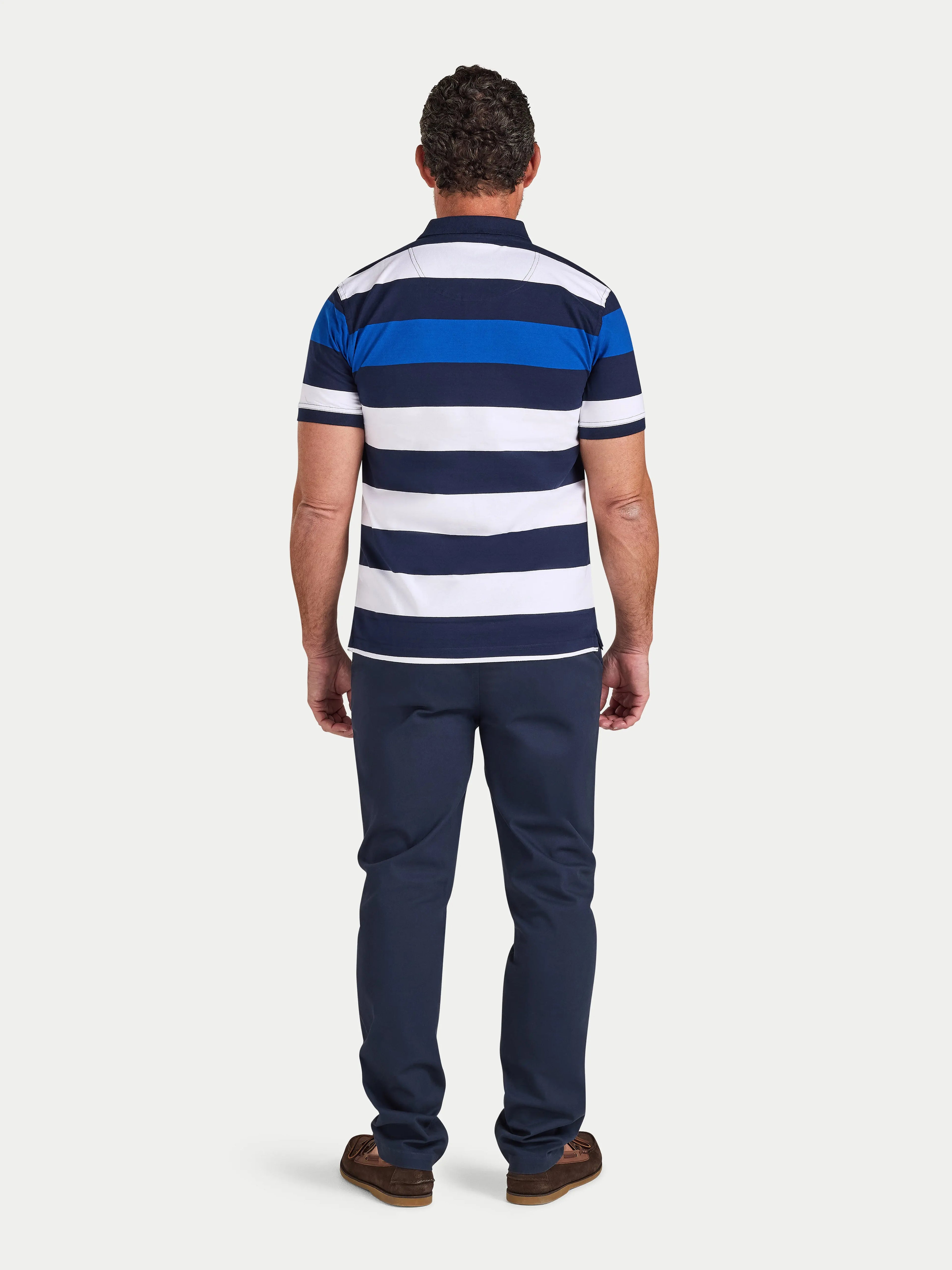 Man wearing a blue and white striped polo shirt and navy pants on a white background