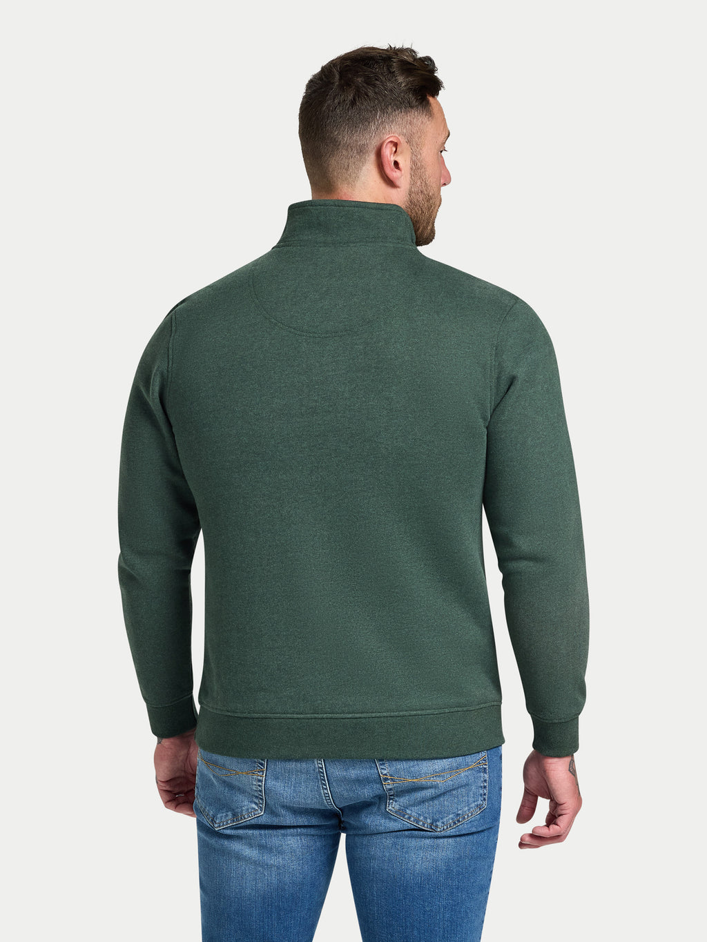 Man wearing a green half-zip sweatshirt and blue jeans on a white background