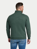 Man wearing a green half-zip sweatshirt and blue jeans on a white background