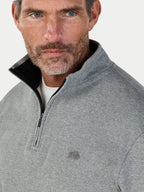 Man wearing a gray half-zip pullover with a logo on a light gray background
