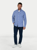 Man wearing a blue checkered shirt and dark pants on a white background
