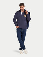 Man wearing a navy blue sweater and jeans on a light gray background
