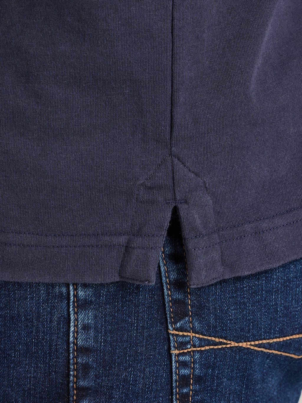 Close-up of a navy blue shirt and blue jeans with stitching details.