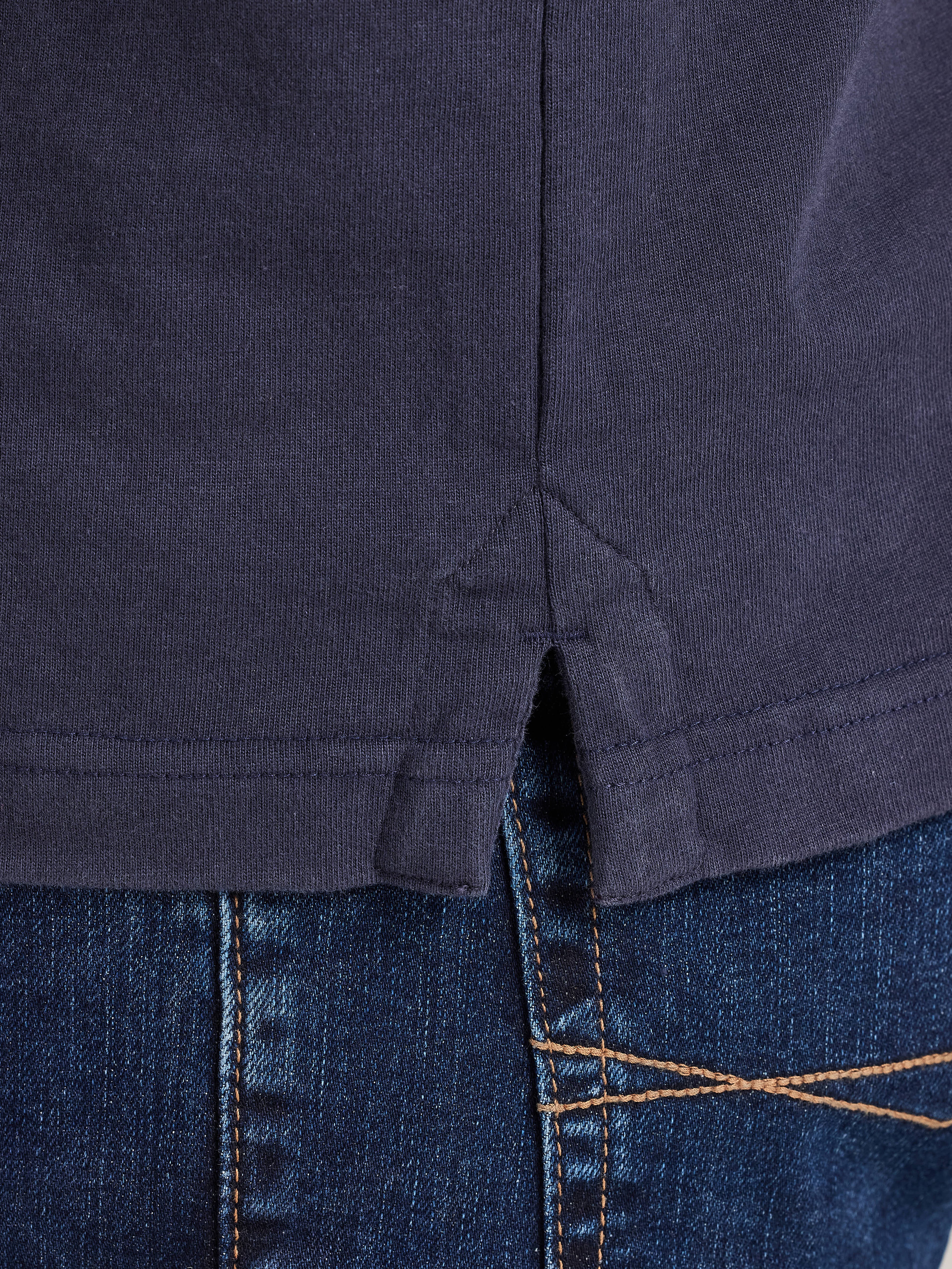 Close-up of a navy blue shirt and blue jeans with stitching details.