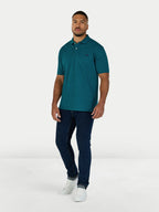 Man wearing a teal polo shirt and dark jeans on a white background