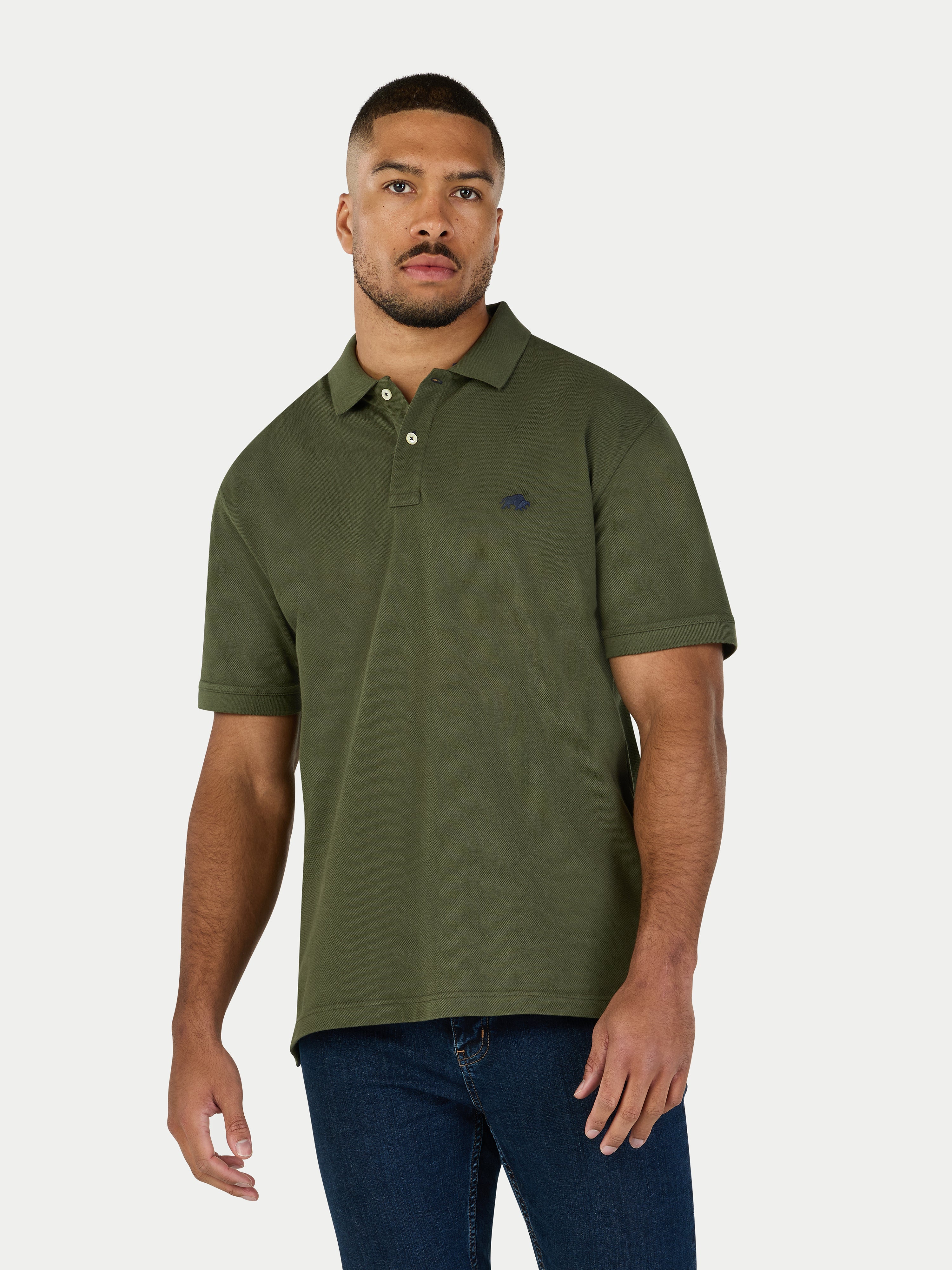 Man wearing a green polo shirt and blue jeans on a white background