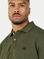 Man wearing a green polo shirt with a logo on a white background