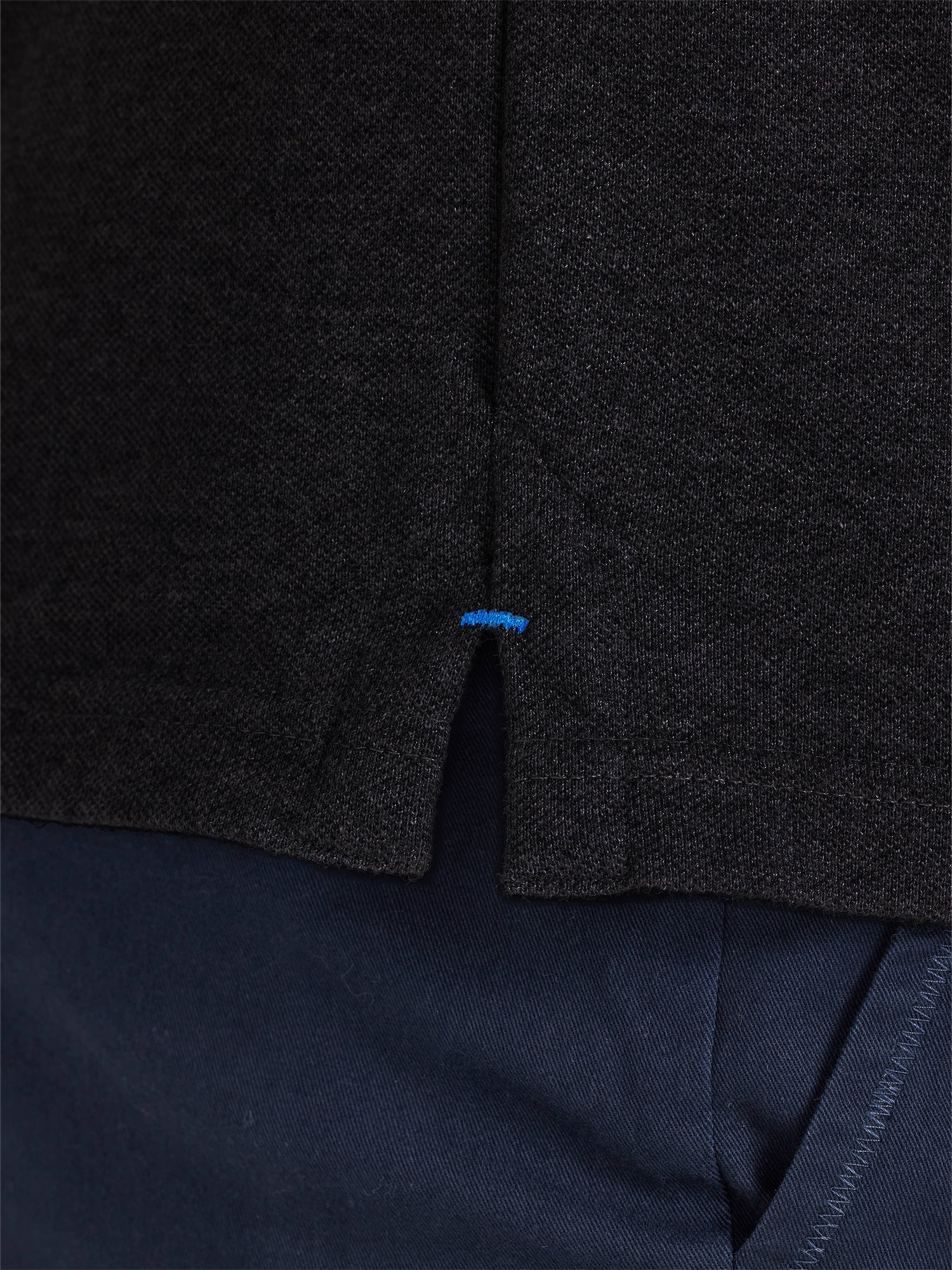 Dark gray textured fabric with a blue tag on a dark background