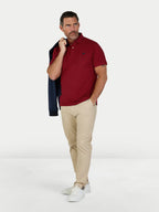 Man wearing a red polo shirt, beige pants, and white sneakers on a white background.