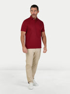 Man wearing a red polo shirt and beige pants on a white background.