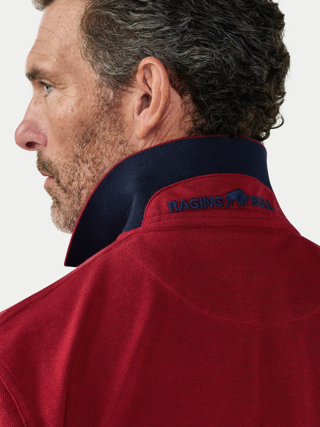 Man wearing a red jacket with 'Raging Bull' logo on a white background.