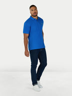 Man wearing a blue polo shirt and dark jeans on a white background