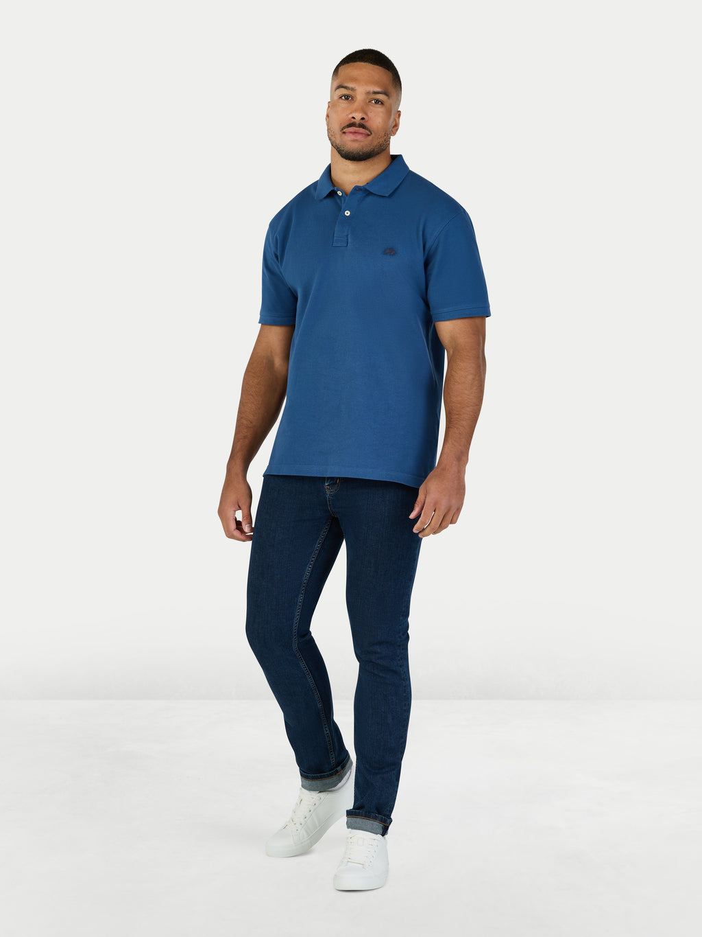 Man wearing a blue polo shirt and jeans on a white background