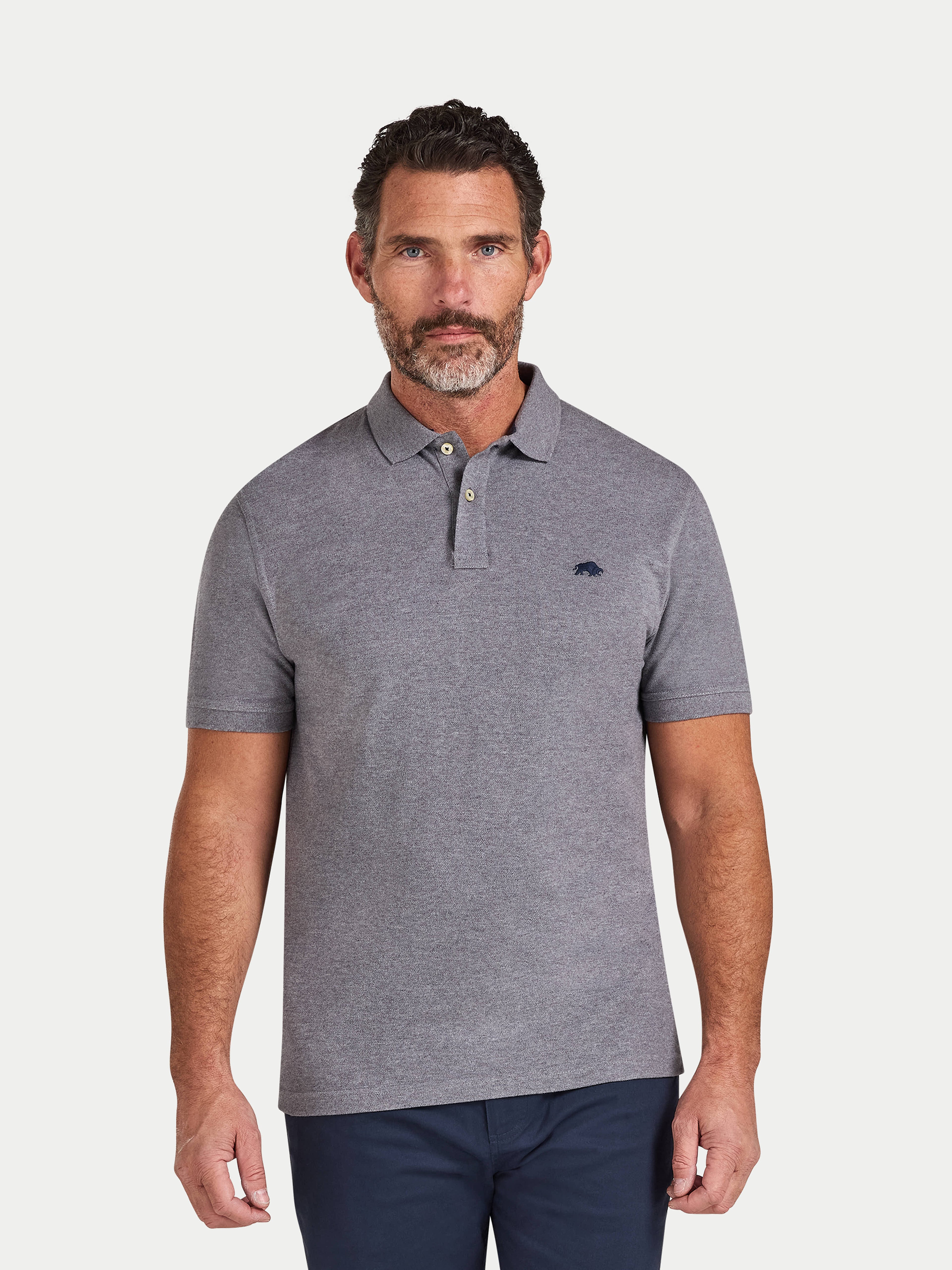 Man wearing a gray polo shirt with a small logo on a white background