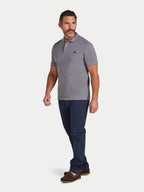 Man wearing a gray polo shirt and navy pants on a white background