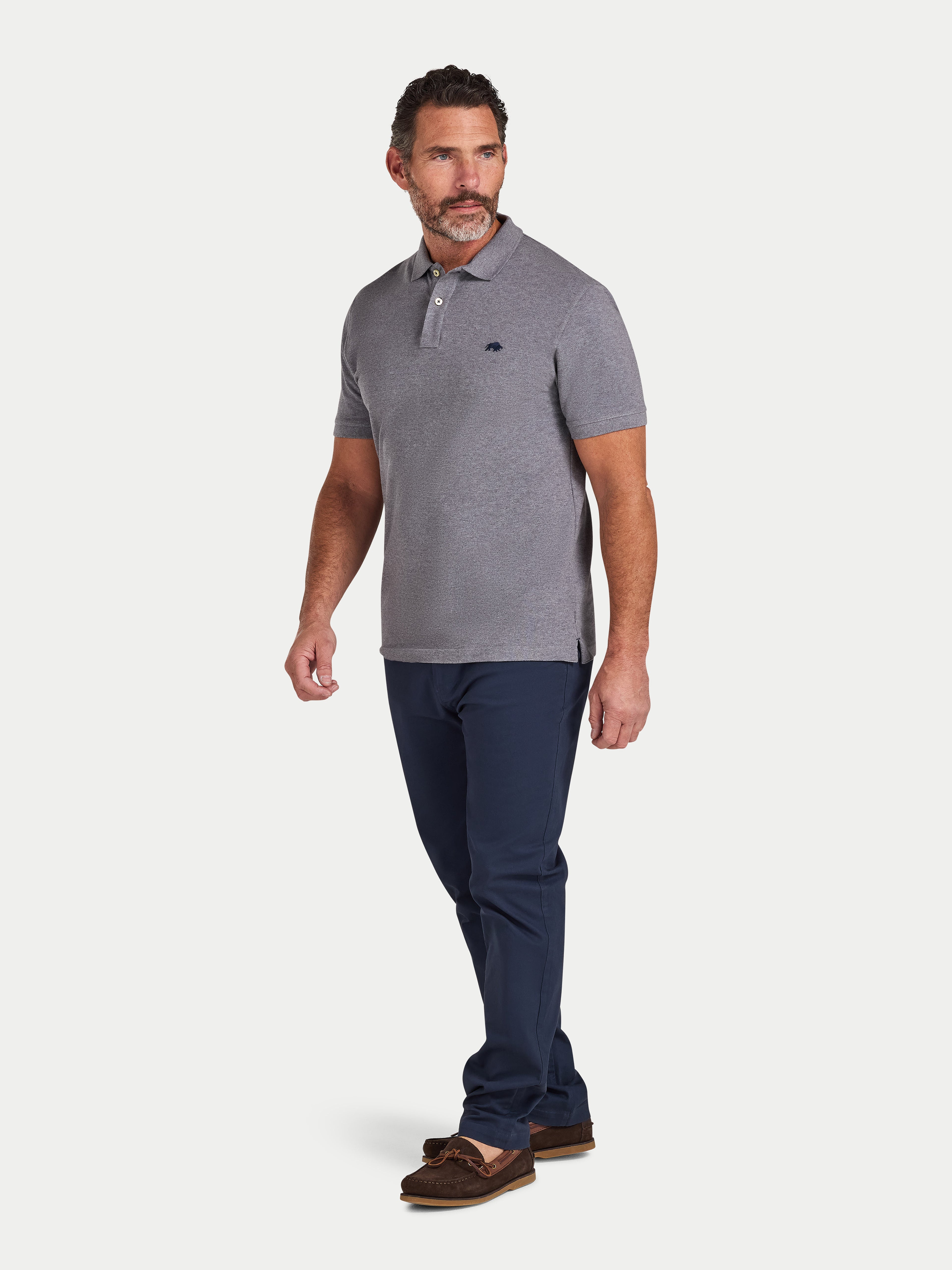 Man wearing a gray polo shirt and navy pants on a white background