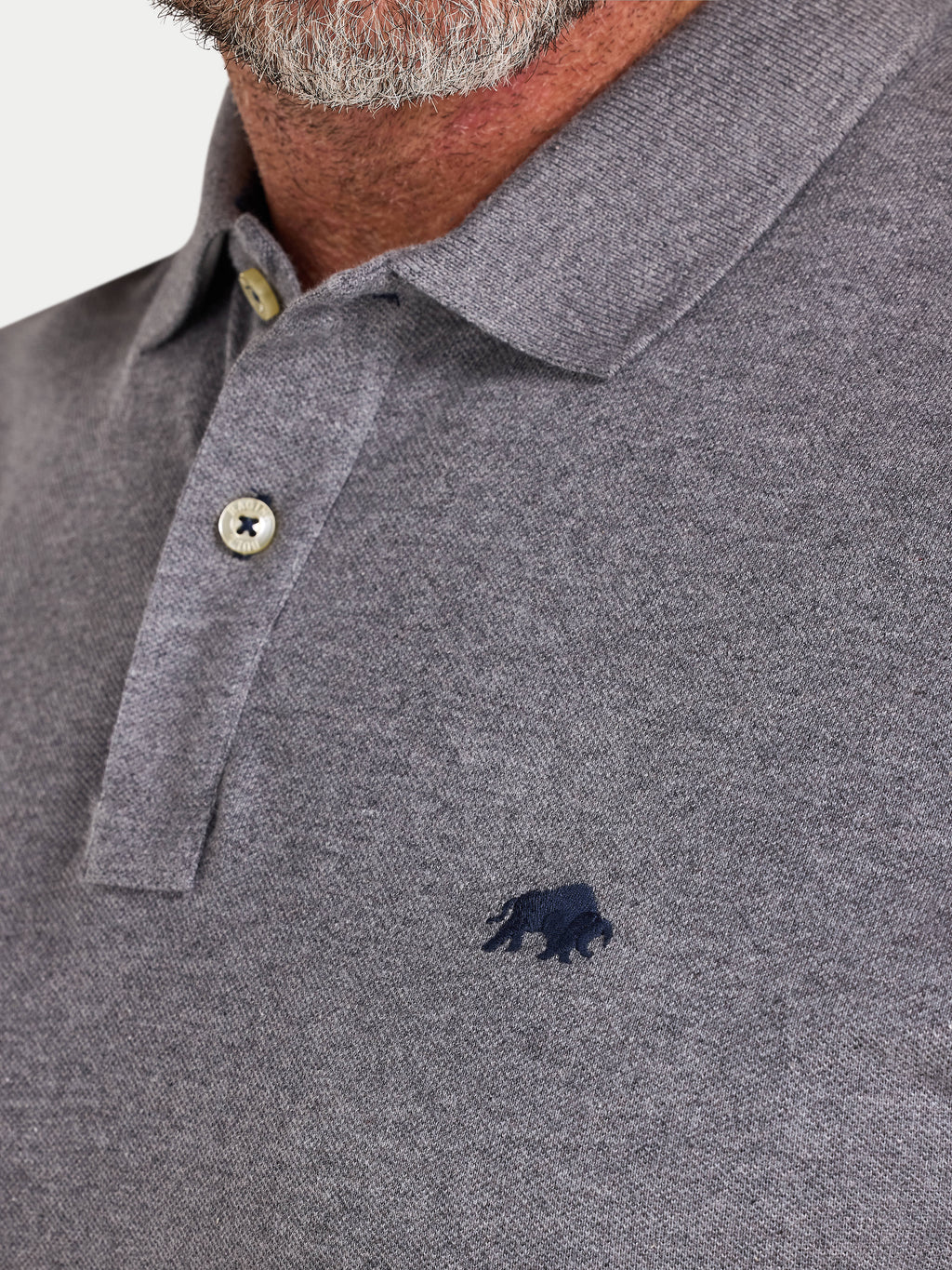 Close-up of a gray polo shirt with a small logo on a white background