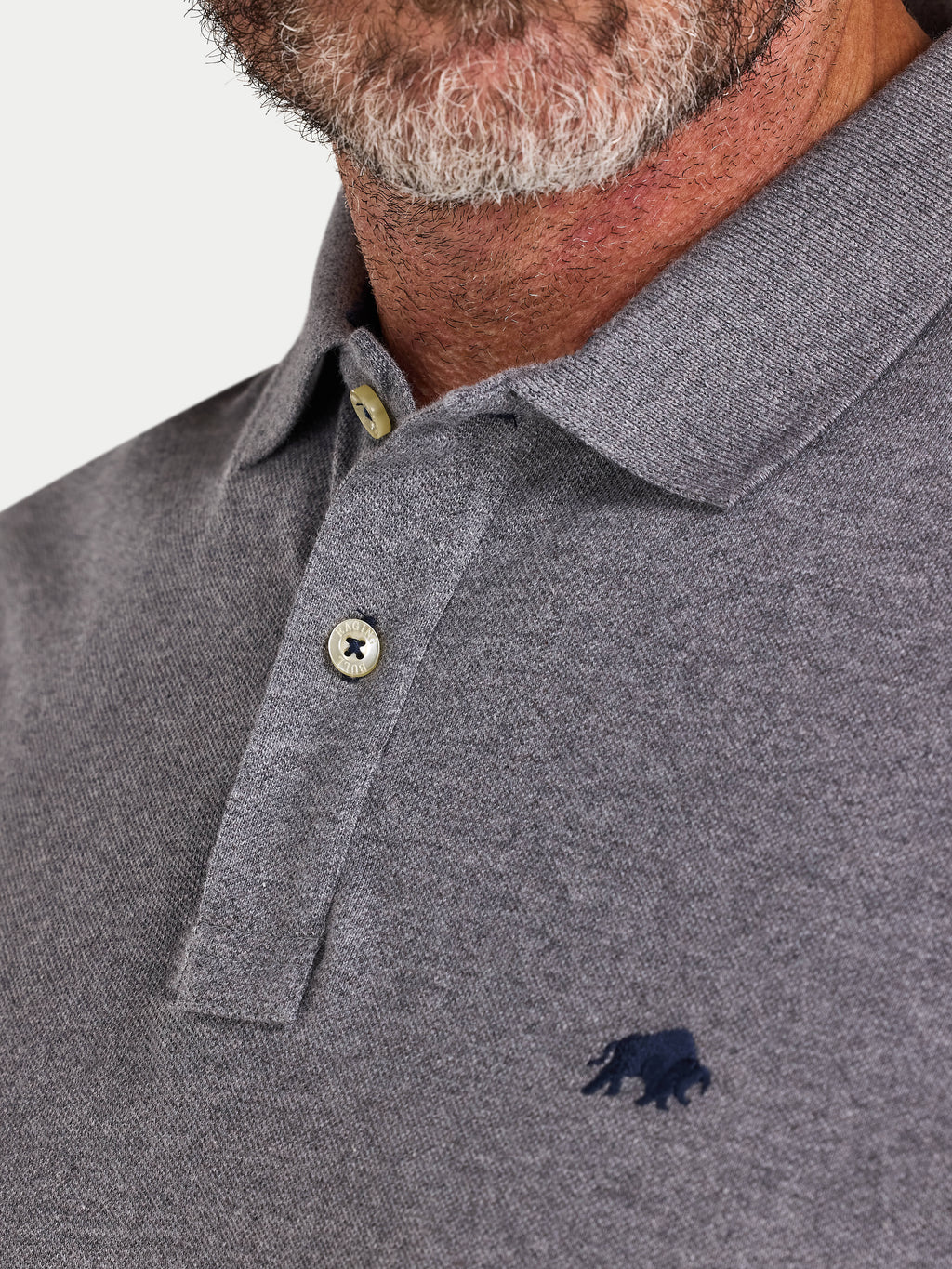 Close-up of a gray polo shirt with a logo on a light gray background