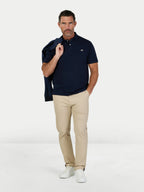 Man wearing a navy polo shirt and beige pants on a white background