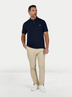 Man wearing a navy polo shirt and beige pants on a white background