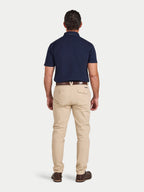 Man wearing a navy polo shirt and beige pants on a white background