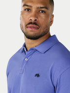 Man wearing a blue polo shirt with a logo on a light gray background