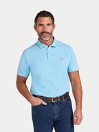 Man wearing a light blue polo shirt with a small red logo on a white background