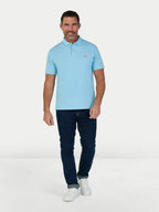 Man wearing a light blue polo shirt and dark jeans on a white background