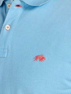 Light blue polo shirt with a pink logo on a plain background