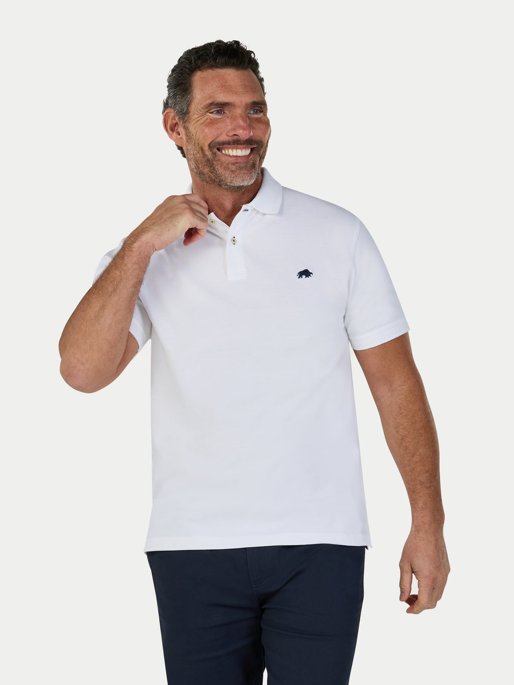 Man wearing a white polo shirt with a small logo on a light gray background