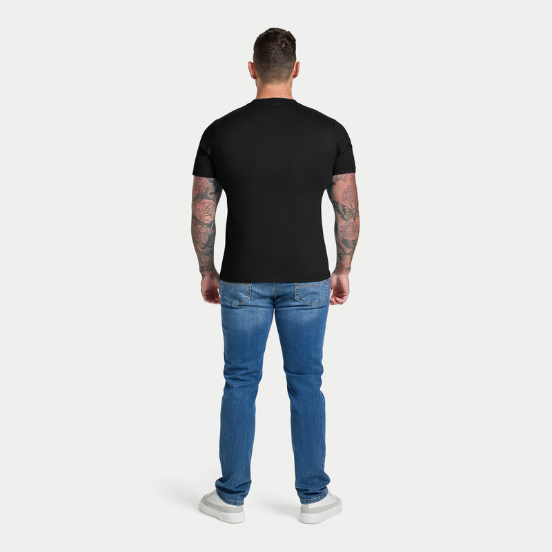 Man wearing a black t-shirt and blue jeans on a white background