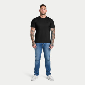 Man wearing a black t-shirt and blue jeans on a white background